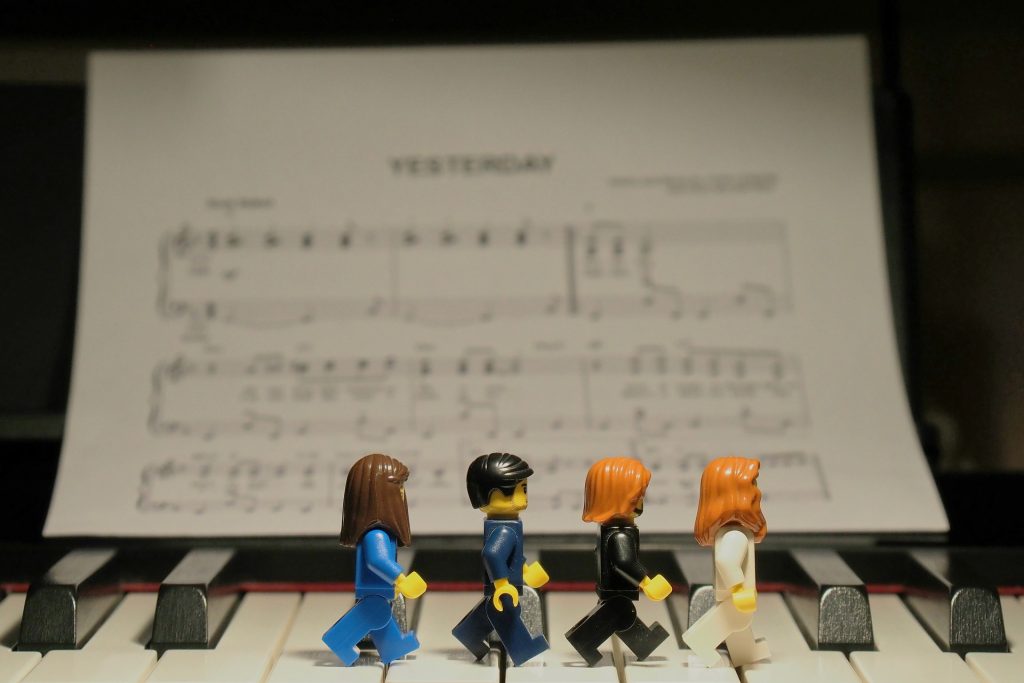 Recréation de la pochette de l'album Abbey Road avec les 4 Beatles en LEGO qui marchent sur un piano sur lequel on peut également voir les partitions du morceau Yesterday