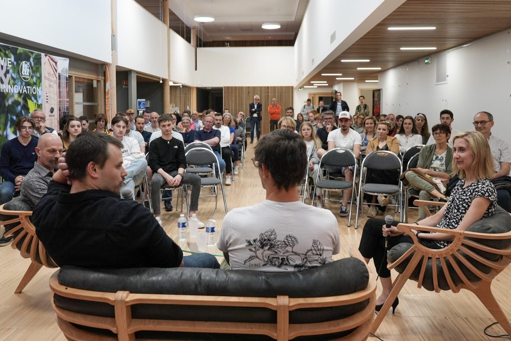 Photo de la conférence In'bô qui montre les intervenants de dos ainsi que l'intégralité du public présent.