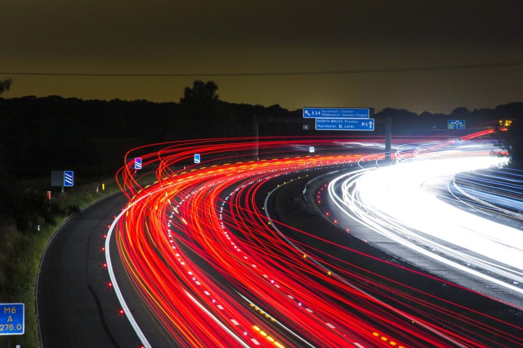 Photo à longue exposition d'un trafic autoroutier qui se traduit par des trainées lumineuses.