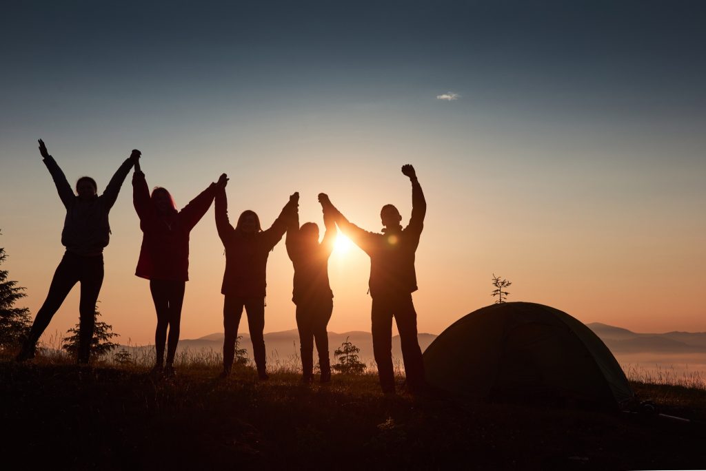 Des silhouettes de gens devant un coucher ou un lever de soleil