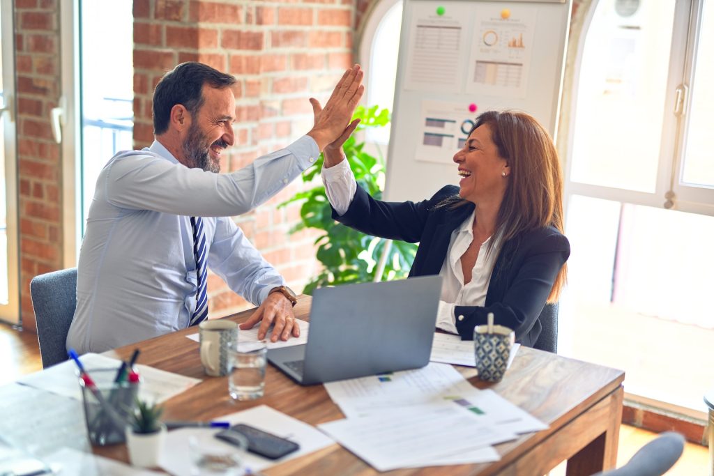 Un homme et une femme d'affaires sont très heureux et se tapent dans les mains.