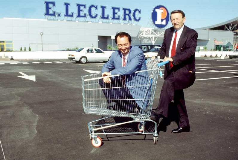 Edouard Leclerc pousse un caddie dans lequel se trouve Michel-Edouard Leclerc sur le parking du supermarché de Blagnac lors de l'inauguration de celui-ci en 1993.