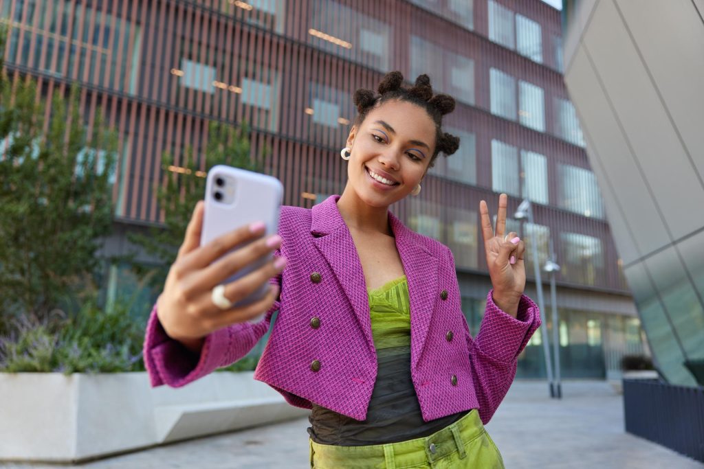 Une jeune femme se prend en photo dans une rue.